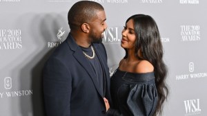 Kanye West looks at Kim Kardashian as she smiles and looks back.