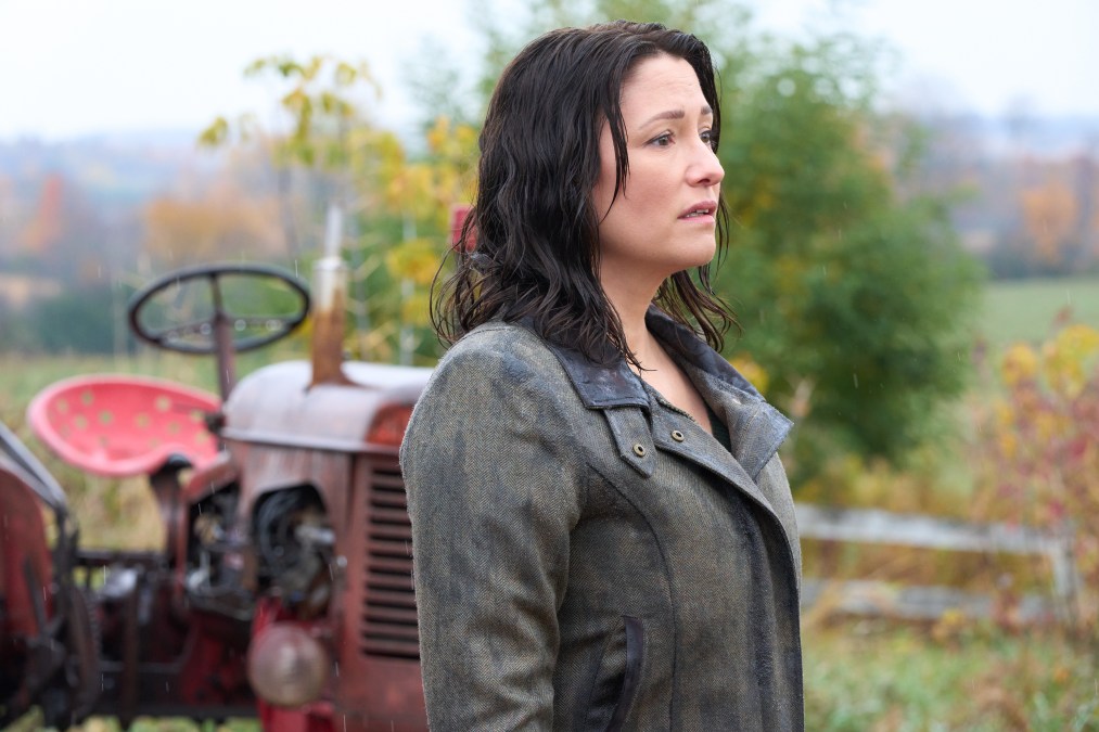 Kat with wet hair standing in front of a tractor looking sad