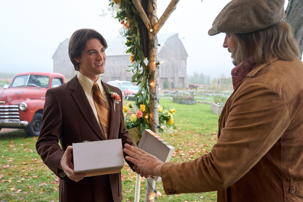 Colton in the 1970s with a box and wearing a brown suit, talking to Jasper