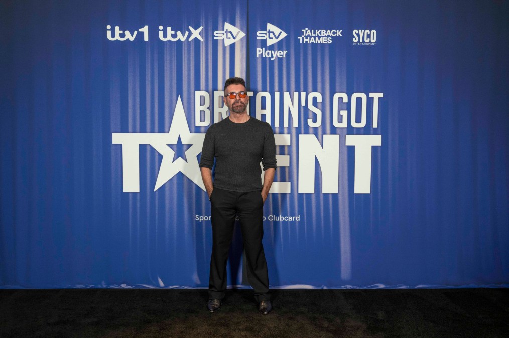 Simon Cowell posing in front of a step and repeat.