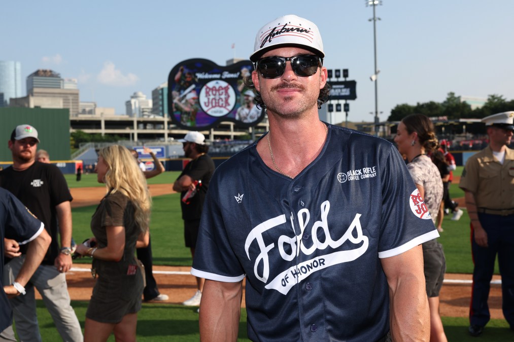 Riley Green posing in a softball jersey