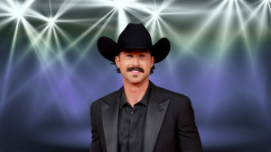 Riley Green posing in an all black formal outfit and cowboy hat.