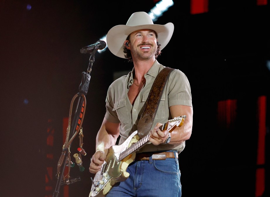 Riley Green smiling while holding a guitar