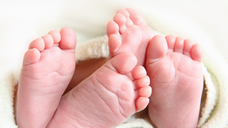 Two pairs of baby feet wrapped in a blanket