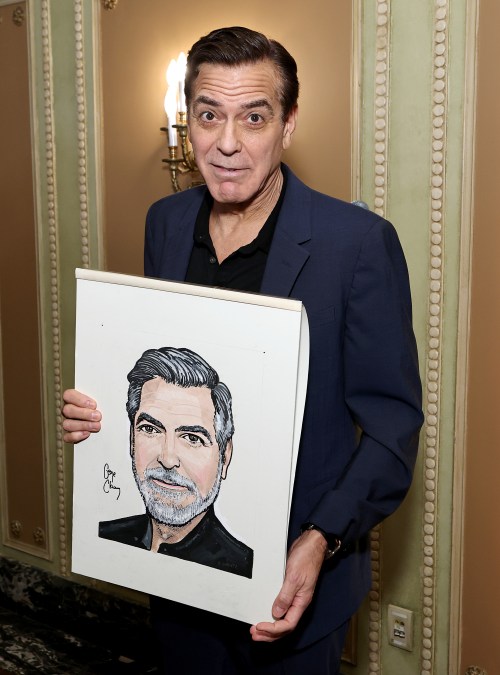 George Clooney attends an event holding his caricature.